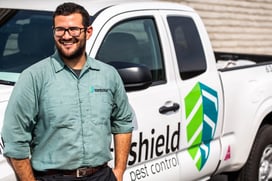 EcoShield pest technician standing and smiling in front of an EcoShield truck